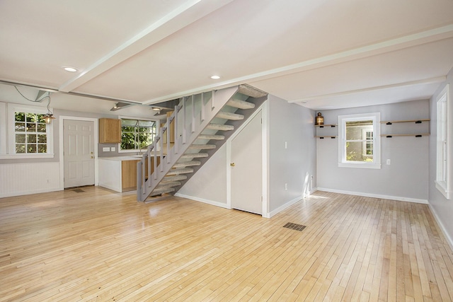 unfurnished living room featuring visible vents, recessed lighting, light wood finished floors, baseboards, and stairs