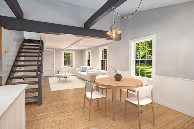 dining room with stairs, beam ceiling, light wood-style floors, and wainscoting