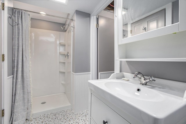 bathroom with wainscoting, a stall shower, and vanity