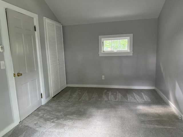 unfurnished bedroom featuring a closet, baseboards, carpet flooring, and vaulted ceiling