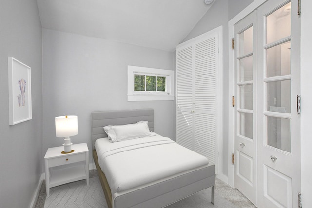 bedroom featuring a closet, baseboards, light carpet, and lofted ceiling