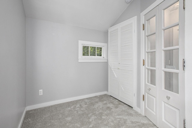 unfurnished bedroom with a closet, baseboards, carpet, and lofted ceiling