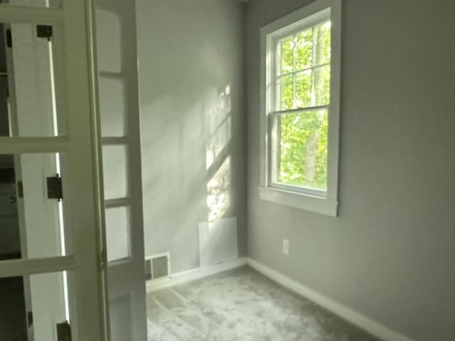 unfurnished room with baseboards, visible vents, and light carpet