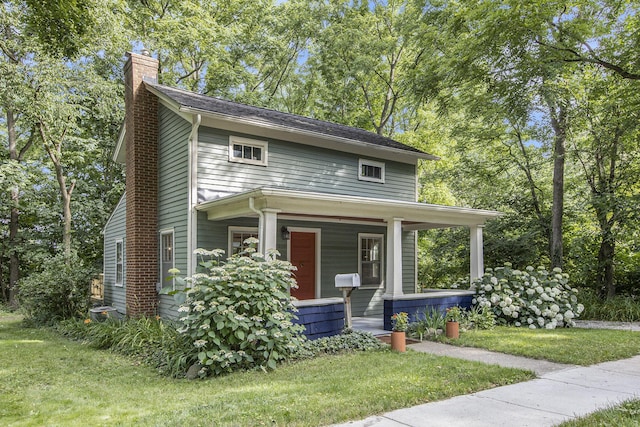 view of front of house featuring a front lawn, a porch, and a chimney