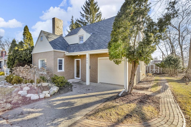 view of front of house featuring stucco siding, a garage, a chimney, and driveway