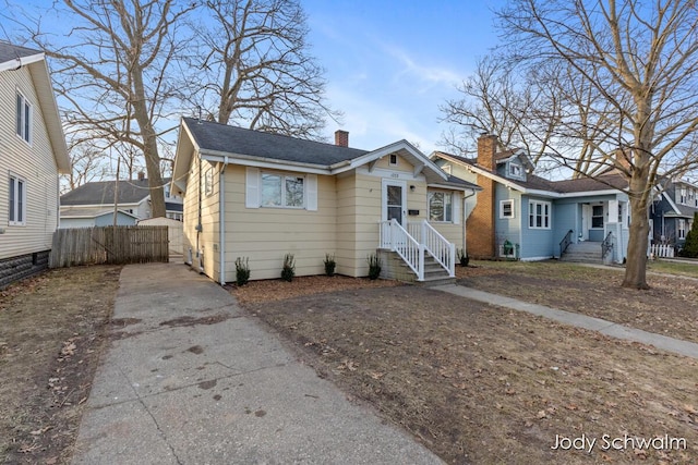 bungalow-style house with a residential view, driveway, a chimney, and fence