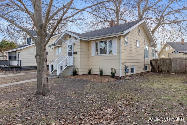 bungalow-style house featuring a chimney and fence