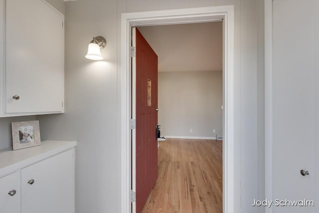 corridor with light wood-style floors and baseboards