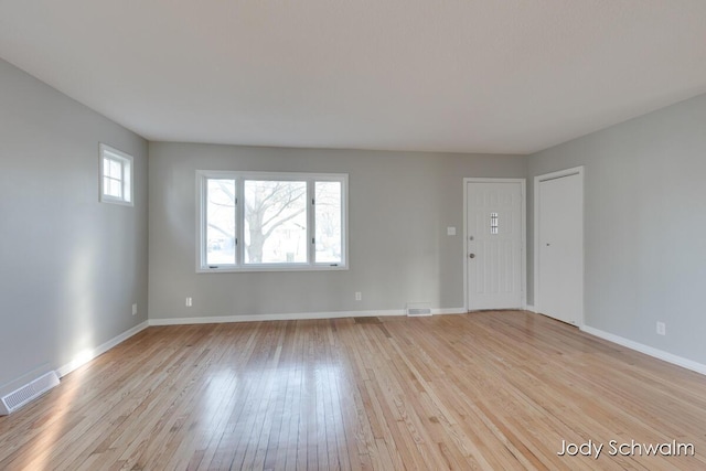 unfurnished living room featuring light wood-type flooring, visible vents, and baseboards