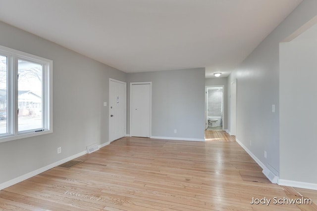 empty room featuring visible vents, baseboards, and light wood-style flooring