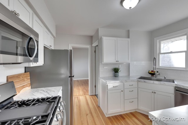 kitchen with white cabinetry, light countertops, appliances with stainless steel finishes, and a sink