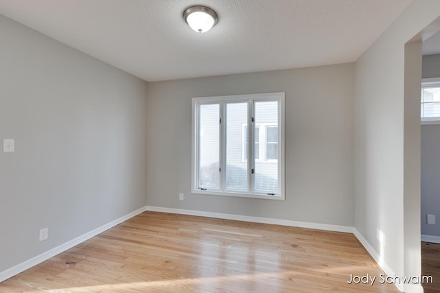 empty room with baseboards, light wood-style floors, and a textured ceiling