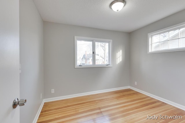 spare room with a textured ceiling, baseboards, and wood finished floors