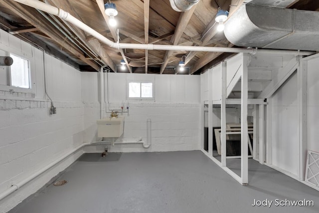 below grade area with concrete block wall, a healthy amount of sunlight, and a sink