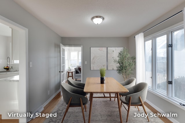 dining space with wood finished floors, baseboards, and a textured ceiling