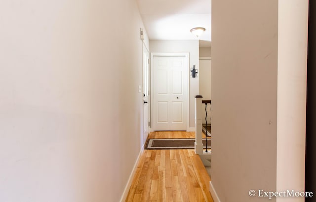 corridor featuring light wood-style flooring and baseboards