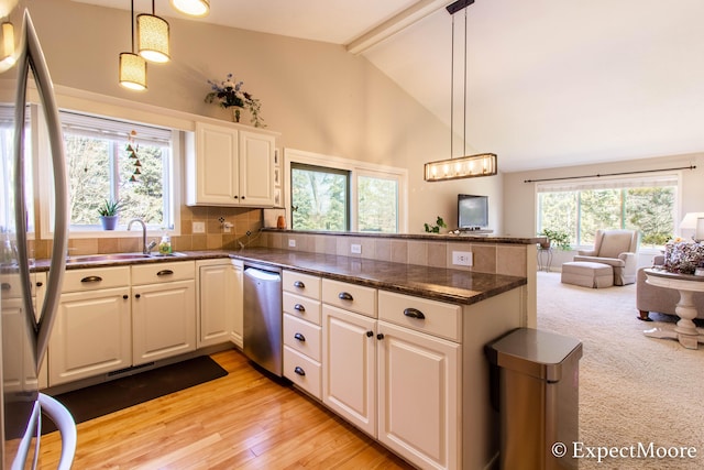 kitchen featuring beam ceiling, a peninsula, a sink, appliances with stainless steel finishes, and backsplash