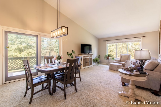 carpeted dining area with high vaulted ceiling and a chandelier