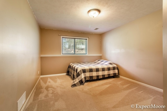 carpeted bedroom featuring baseboards, visible vents, and a textured ceiling