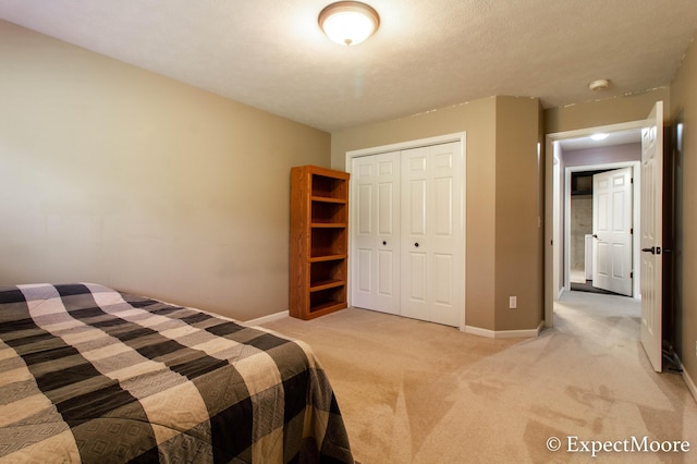 unfurnished bedroom featuring a closet, light colored carpet, a textured ceiling, and baseboards