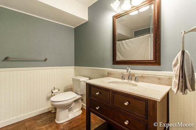 full bath featuring a wainscoted wall, toilet, wood finished floors, and vanity