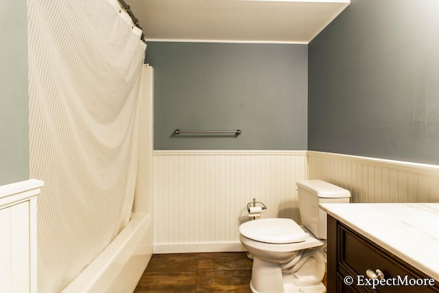 bathroom with shower / bath combo with shower curtain, toilet, wainscoting, wood finished floors, and vanity