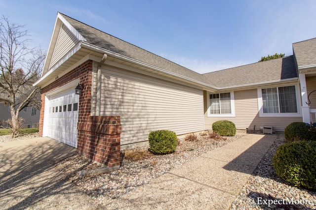 view of home's exterior featuring driveway, a garage, and roof with shingles