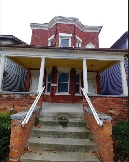 view of front of home with brick siding and a porch