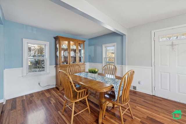 dining space with wood finished floors, visible vents, and a wainscoted wall