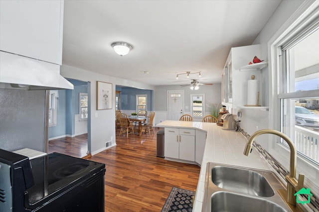 kitchen with dark wood-type flooring, black electric range, a sink, a peninsula, and ceiling fan