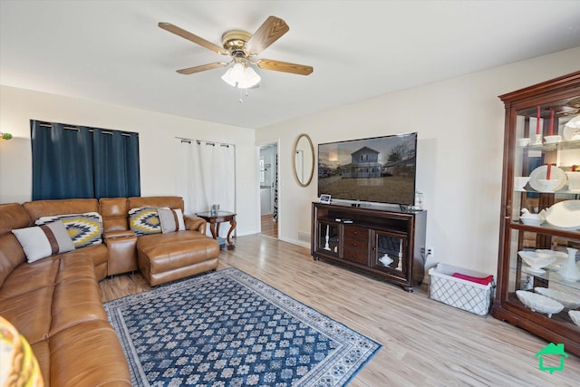 living room featuring wood finished floors, baseboards, and ceiling fan