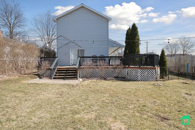 rear view of house with a deck, a yard, and fence