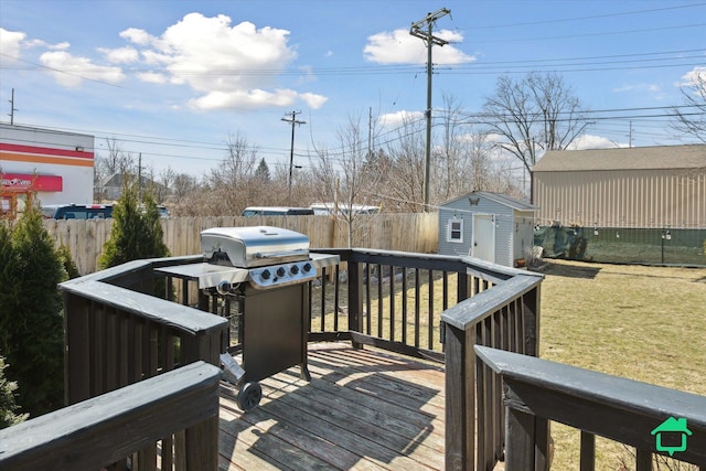 deck with grilling area, a yard, a fenced backyard, an outbuilding, and a storage unit