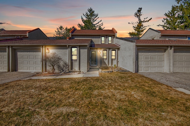 view of front of property with brick siding, an attached garage, driveway, and a front yard