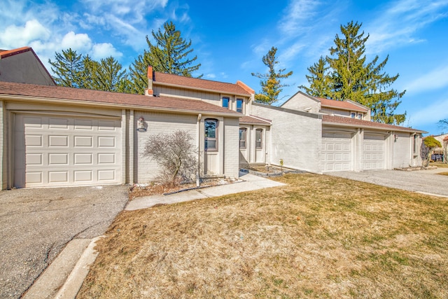 view of front of home with brick siding, a front yard, an attached garage, and driveway