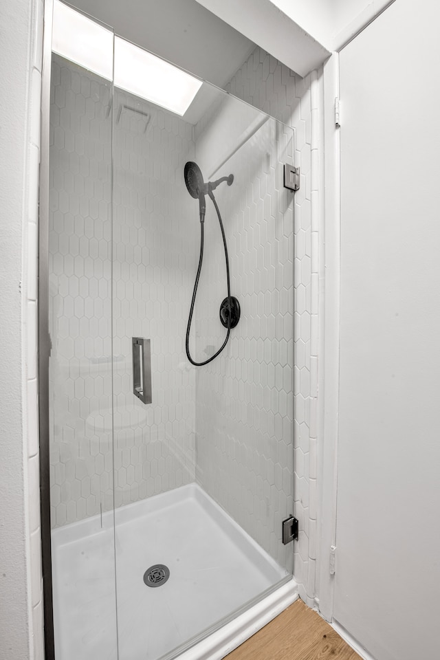 bathroom with wood finished floors and a stall shower