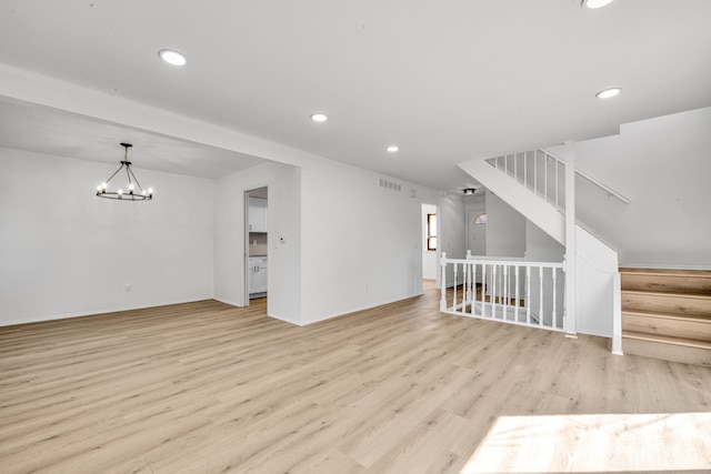 unfurnished living room featuring visible vents, recessed lighting, stairs, a notable chandelier, and light wood-type flooring