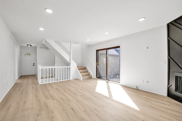 unfurnished living room with stairs, recessed lighting, light wood-style floors, and baseboards