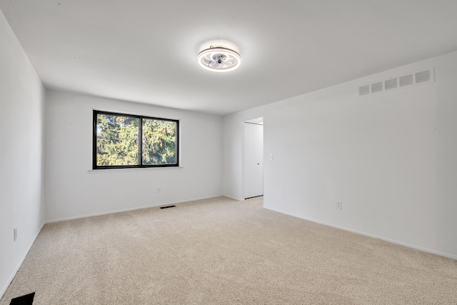 unfurnished room featuring baseboards, visible vents, and light carpet