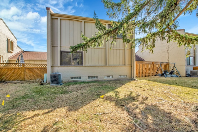 view of side of property with cooling unit, a lawn, board and batten siding, and fence private yard