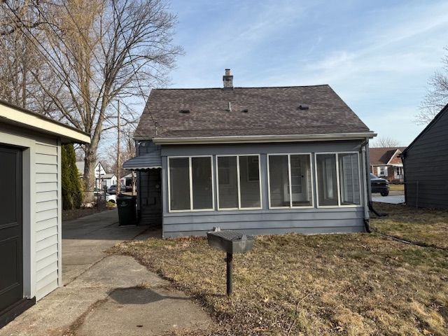 rear view of house featuring a chimney and a sunroom