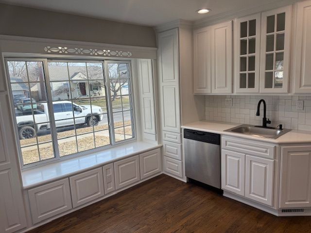 kitchen with a sink, dishwasher, white cabinets, and light countertops