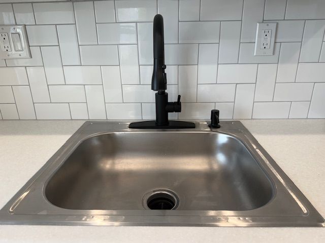 details with tasteful backsplash, light countertops, and a sink