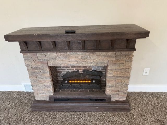 interior details featuring a stone fireplace and baseboards