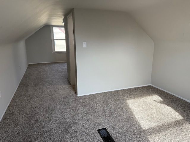 bonus room with vaulted ceiling, visible vents, and carpet floors