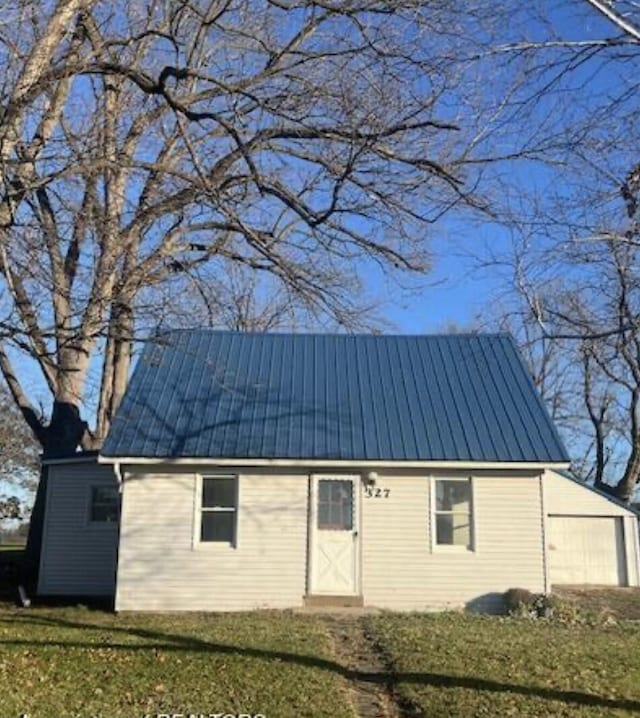 rear view of property featuring a yard, a garage, and metal roof