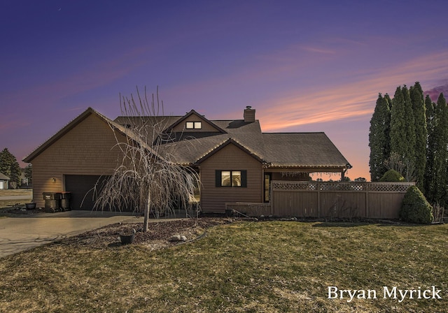 view of front facade with fence, concrete driveway, a front yard, a chimney, and a garage