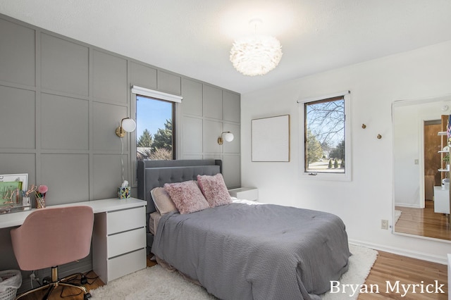 bedroom featuring a decorative wall, multiple windows, and a chandelier