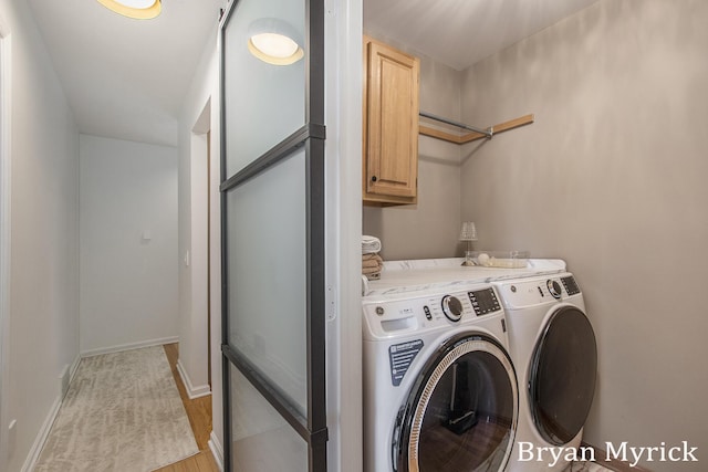 clothes washing area featuring washer and dryer, cabinet space, baseboards, and light wood finished floors