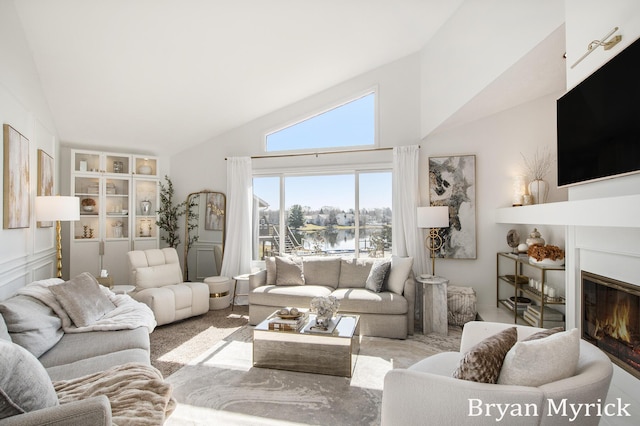 living area featuring high vaulted ceiling and a glass covered fireplace